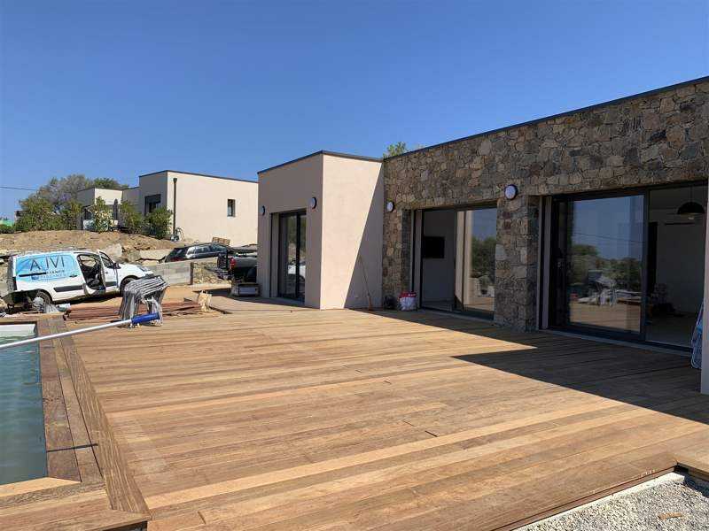 La terrasse en bois et la piscine, au bord de la pièce de vie.